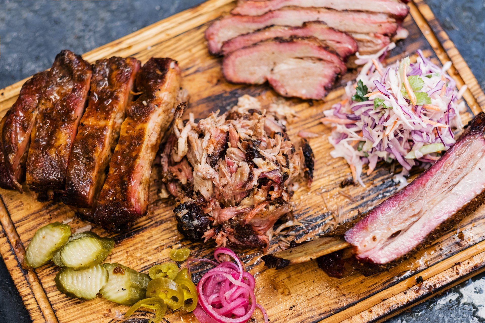 Premium BBQ spread with sliced brisket, pulled pork, ribs, and fresh sides at Scootrz Deli & BBQ