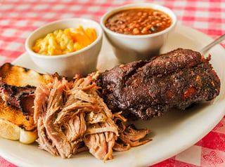 Smoked tri-tip sliced on wooden board with BBQ sauce
