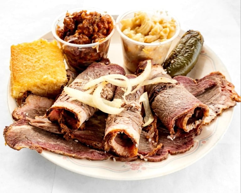 Deli meats platter with sliced beef, bacon, cornbread, and sides