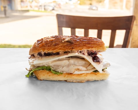 Gourmet sandwich with turkey, brie cheese, and cranberry sauce on a croissant served on a white plate