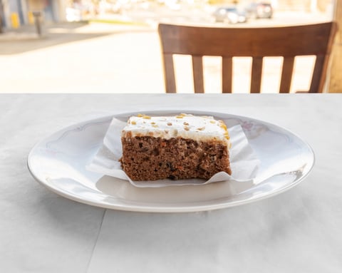 Slice of chocolate cake with white frosting on a white plate sitting on a table